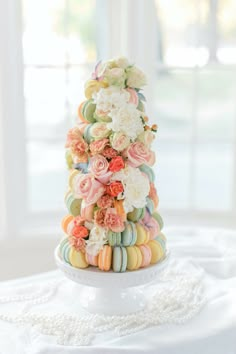 a wedding cake made out of macaroons and flowers on a white tablecloth