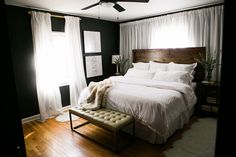 a bed with white sheets and pillows in a bedroom next to a wooden flooring