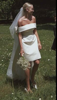 a woman in a wedding dress walking through the grass