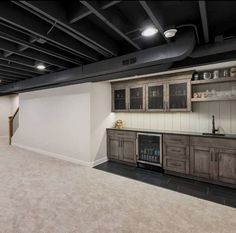 an empty room with wood cabinets and tile flooring in the center is lit by recessed lighting