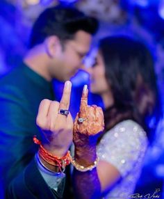 a man and woman making the peace sign with their fingers in front of blue lights