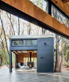 the inside of a small house with wood floors and windows on one side, surrounded by trees