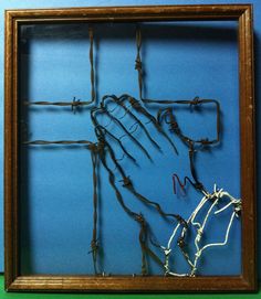 a frame with barbed wire in the shape of a hand and cross on blue background