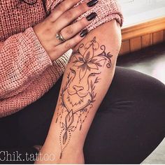 a woman's arm with a tattoo on it that has a lion and flowers