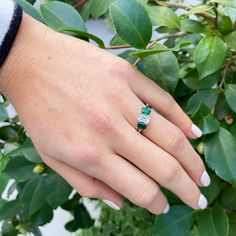 This three-stone engagement ring features an emerald-cut diamond center flanked by a pair of emerald-cut emeralds prong-set in a platinum mounting. Center Diamond Total Weight: 1.13 ct Shape: Emerald-Cut Color: F Clarity: SI1 Side Emerald Total Weight: 1.08 ct Shape: Emerald-Cut Color: bluish-green hue, medium dark tone, strong to vivid saturation Clarity: slightly included Ring Size: 7 Excluded from all discounts and promotions.