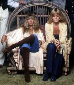 two women sitting on a wicker chair in front of a man and another woman