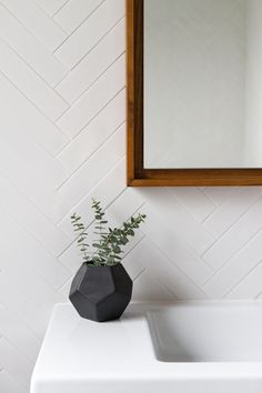 a bathroom sink with a mirror above it and a vase on the counter next to it