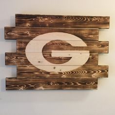 a wooden sign with the letter g painted on it's side, hanging from a wall