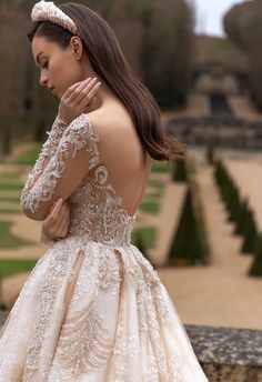 a woman in a wedding dress looking down at her hand on her shoulder and the back of her head