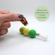 a hand is holding a bottle with some small balls on it and a dropper in the middle