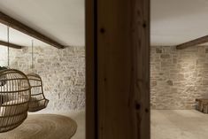 a bird cage hanging from the ceiling in a living room with stone walls and exposed beams