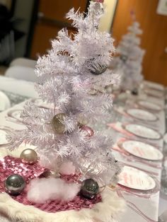 a small white christmas tree sitting on top of a table next to plates and silverware