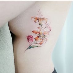 a close up of a woman's stomach with flowers tattooed on the side of her body