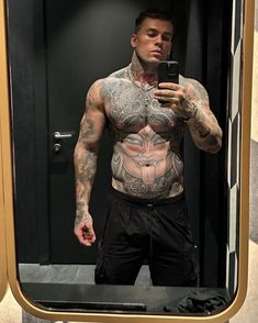 a man taking a selfie in front of a mirror with tattoos on his chest