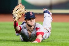 a baseball player is laying on the ground with his glove up in the air, and he's about to throw the ball