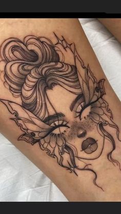 a woman's leg with an artistic tattoo design on the thigh and her face