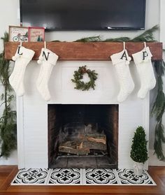 a fireplace decorated for christmas with stockings hanging from the mantel and wreath on top