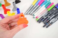 someone holding an orange plastic key in front of markers