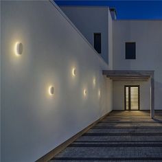 a white building with three lights on the side of it's wall and an open door