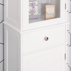 a white cabinet with two drawers and some boxes on it's top, in front of a tiled wall