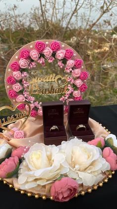 two wedding rings sitting on top of a plate with pink and white flowers in it