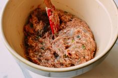 a bowl filled with food sitting on top of a table next to a wooden spoon