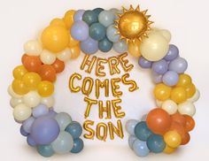 there is a balloon wreath with the words here comes the son