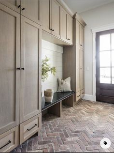 an entryway with built in cabinets and a potted plant sitting on the bench