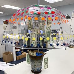 an umbrella made out of dollar bills and other items on a table in an office cubicle