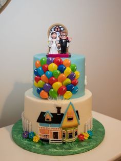 a wedding cake decorated with balloons and a bride and groom standing on the top tier