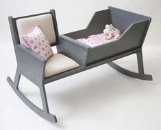 a toy rocking chair with a baby's bed in the middle and pillows on it