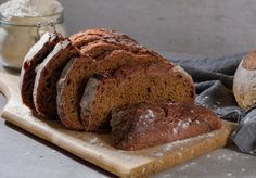 a loaf of bread sitting on top of a wooden cutting board next to some flour