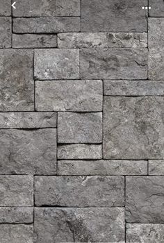 a stone wall that looks like it has been made out of grey bricks and is very high