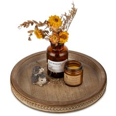 a wooden tray with a jar of honey and a hedge on it next to some flowers