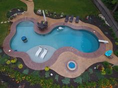 an aerial view of a swimming pool surrounded by landscaping