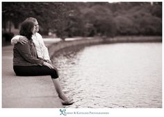 a woman sitting on the edge of a lake