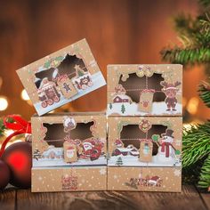 three boxes with christmas decorations on them sitting in front of a christmas tree and bauble