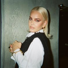 a woman with blonde hair wearing a white shirt and black vest