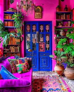 a living room filled with lots of colorful furniture and bookshelves next to a blue door