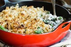 a red casserole dish with green beans and rice in it on a wooden table