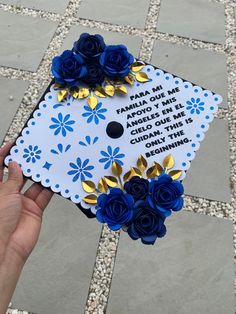 a hand holding a graduation cap with blue flowers on it that says, pare me fam