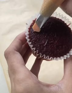 a person holding a cupcake with a knife in it