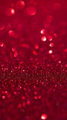 red glitter wallpaper with lots of small dots on it's surface and blurry lights in the background