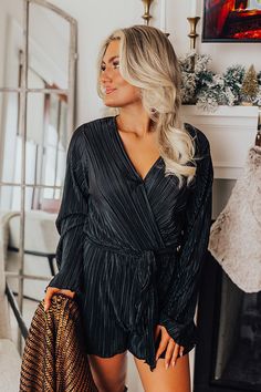 - Style this luxe romper with a chic pair of boots for a trendy look! - Unlined pleated material with a satin finish - A v-cut neckline with a hidden button closure for additional coverage - Long, loose sleeves - An elastic waistline with belt loops and a detachable tie closure belt - A flowy yet flattering romper silhouette that ends in ruffled upper thigh length hemlines