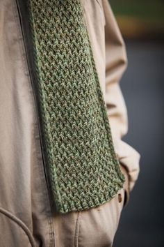 a close up of a person wearing a green knitted necktie and tan jacket