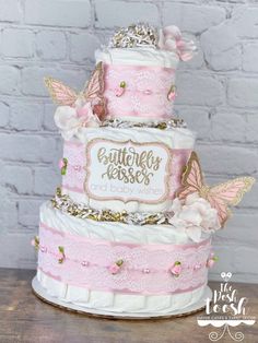 a three tiered cake decorated with pink and white flowers, butterflies and the words butterfly kisses on it