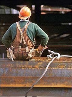 a man standing on top of a truck holding a wrench and wearing a hard hat