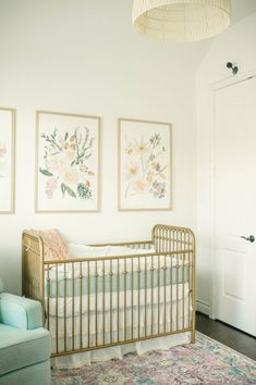 a baby's crib in the corner of a room with two paintings on the wall