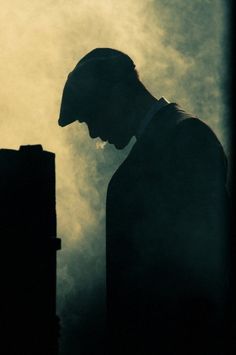 the silhouette of a man in a suit and tie looking down at his cell phone