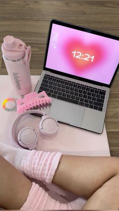 a laptop computer sitting on top of a table next to a pink towel and cup